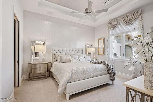 carpeted bedroom featuring visible vents, a raised ceiling, baseboards, and a ceiling fan