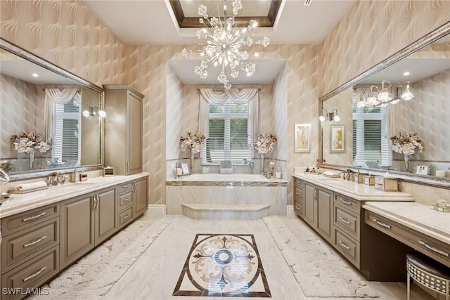 full bathroom featuring wallpapered walls, a tray ceiling, two vanities, a bath, and a chandelier