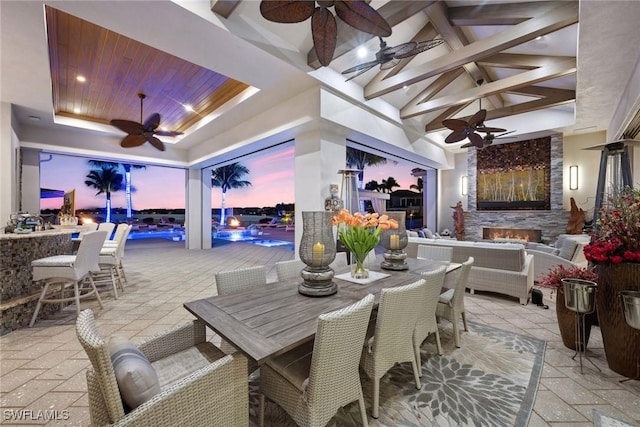 patio terrace at dusk featuring outdoor dining space, ceiling fan, outdoor dry bar, and an outdoor hangout area