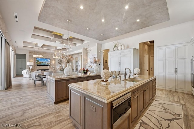 kitchen featuring a chandelier, open floor plan, a large island, coffered ceiling, and a sink