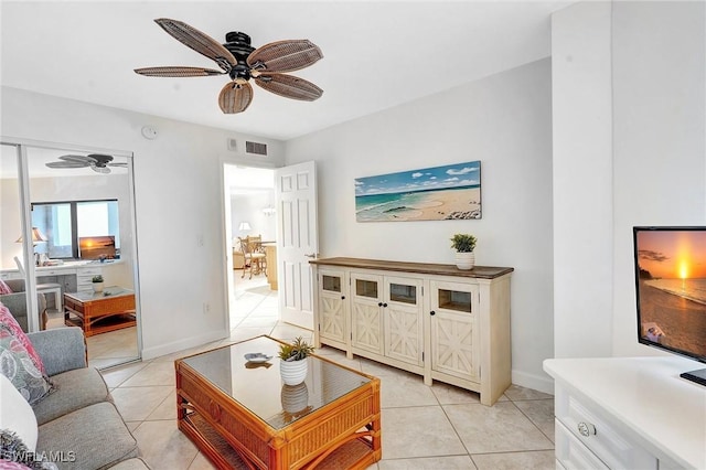 living area featuring light tile patterned floors, baseboards, visible vents, and ceiling fan