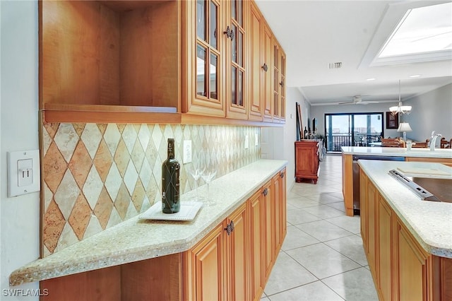 kitchen with visible vents, glass insert cabinets, light tile patterned floors, decorative backsplash, and ceiling fan with notable chandelier