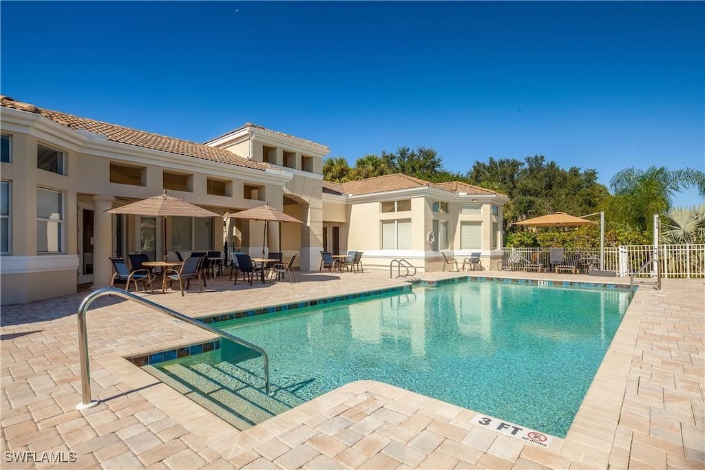 community pool with a patio and fence