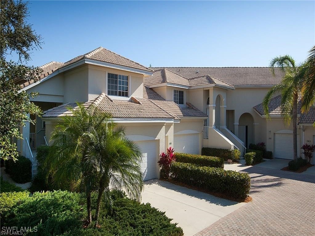 mediterranean / spanish home featuring a garage, a tiled roof, decorative driveway, and stucco siding