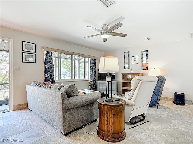 living area with baseboards, visible vents, and ceiling fan