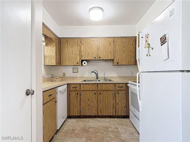 kitchen with brown cabinets, a sink, stone finish flooring, white appliances, and light countertops