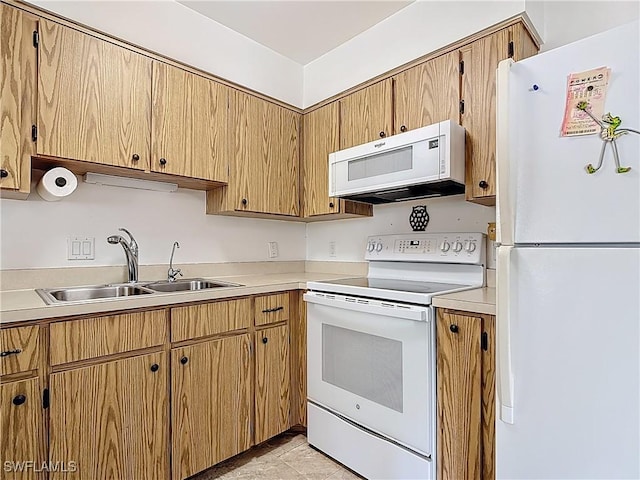 kitchen with a sink, white appliances, and light countertops