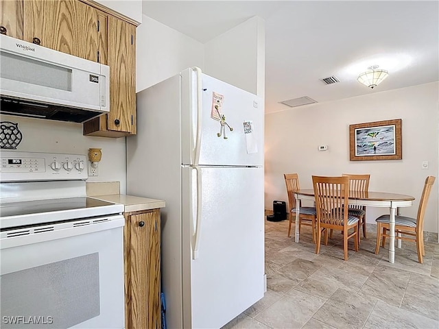 kitchen with visible vents, baseboards, light countertops, brown cabinets, and white appliances