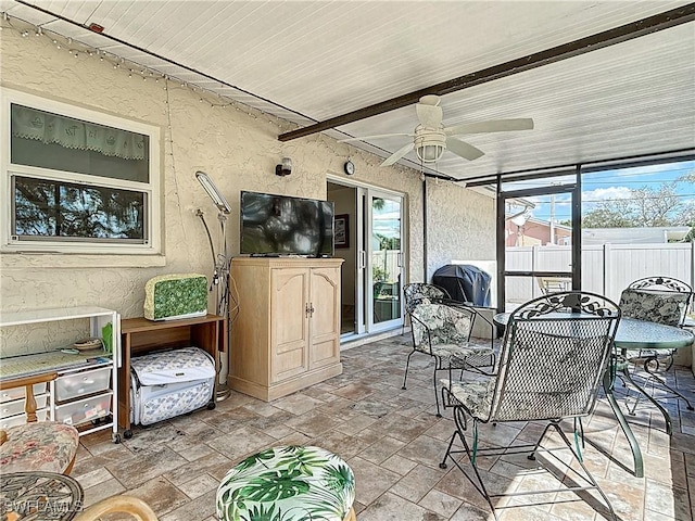 sunroom / solarium featuring a wealth of natural light, beamed ceiling, and a ceiling fan