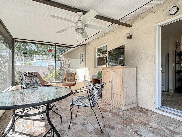 sunroom with beam ceiling, wood ceiling, and ceiling fan