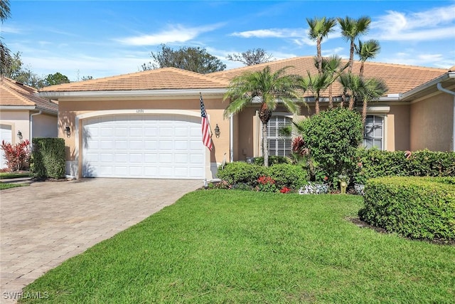 view of front of house featuring decorative driveway, a front yard, an attached garage, and stucco siding