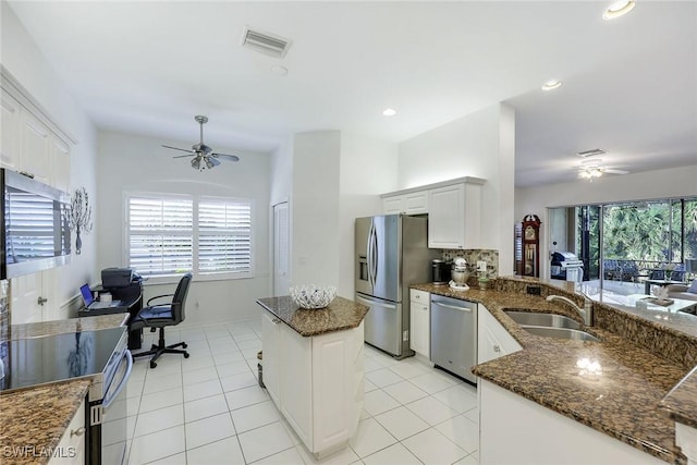 kitchen with visible vents, ceiling fan, dark stone counters, stainless steel appliances, and a sink