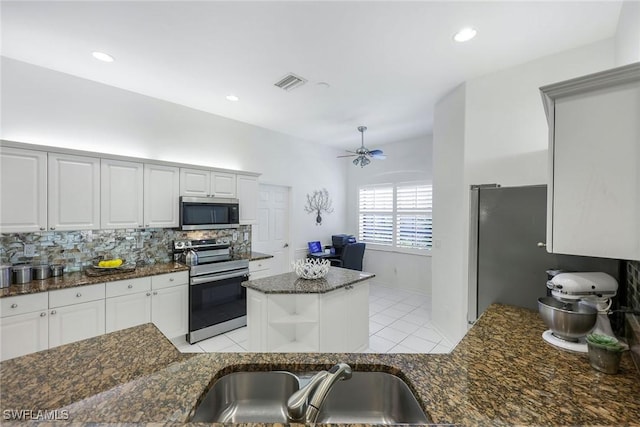 kitchen with visible vents, backsplash, a kitchen island, appliances with stainless steel finishes, and a sink