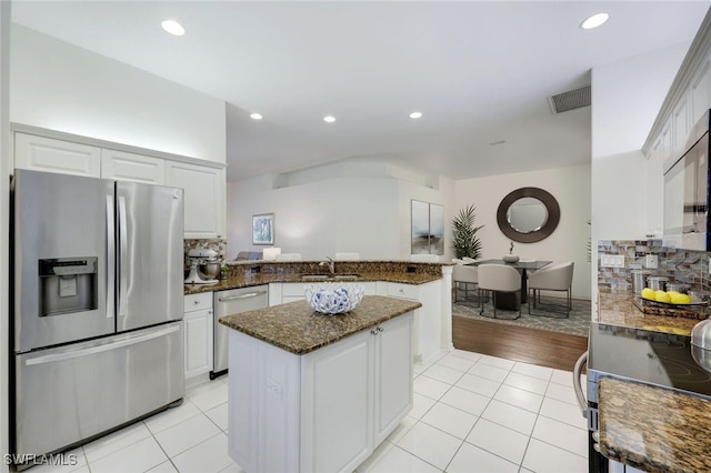 kitchen with visible vents, light tile patterned floors, appliances with stainless steel finishes, a peninsula, and a sink