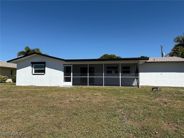 back of house with a lawn, a sunroom, and stucco siding