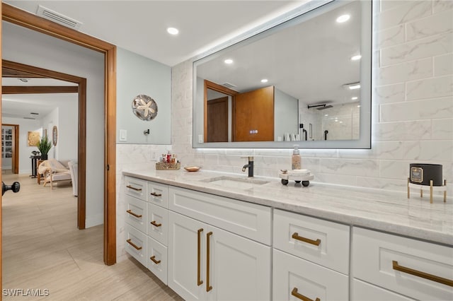 bathroom featuring vanity, tasteful backsplash, a shower, and visible vents