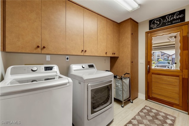 clothes washing area with cabinet space and washing machine and dryer