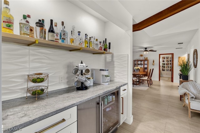 bar with wine cooler, beamed ceiling, decorative backsplash, a bar, and a ceiling fan