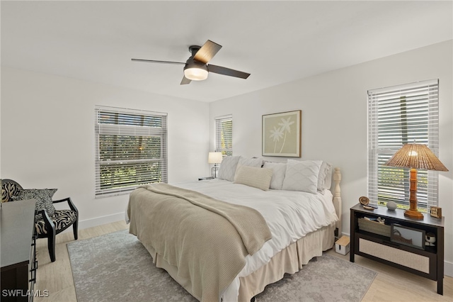 bedroom featuring a ceiling fan, light wood-style floors, and baseboards