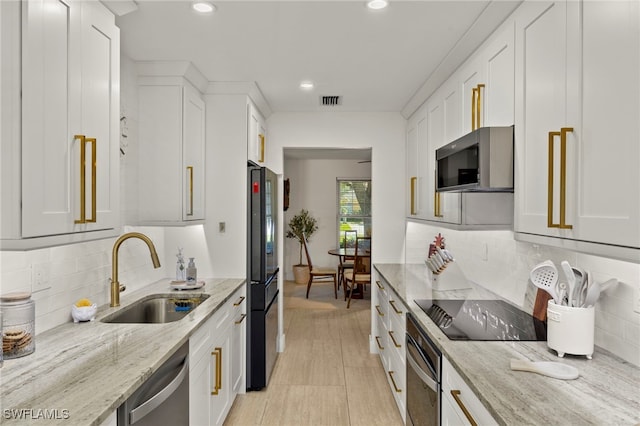 kitchen with a sink, black appliances, and white cabinetry