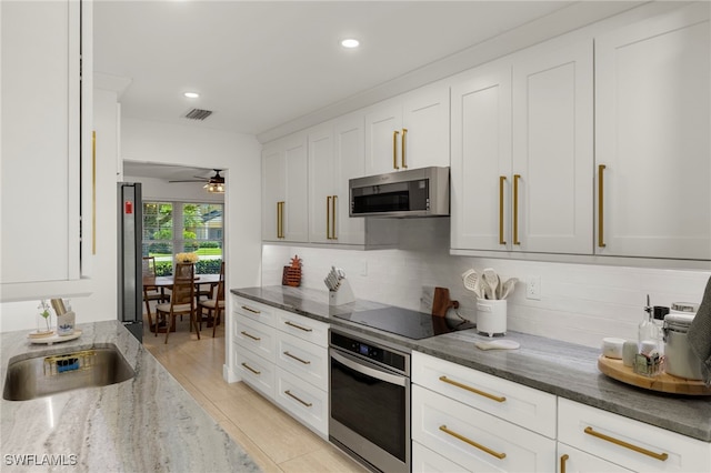 kitchen featuring visible vents, tasteful backsplash, white cabinetry, dark stone counters, and appliances with stainless steel finishes