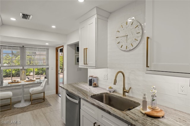 kitchen featuring dishwasher, light stone counters, decorative backsplash, white cabinets, and a sink