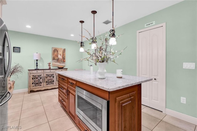 kitchen featuring visible vents, stainless steel appliances, brown cabinetry, light tile patterned floors, and hanging light fixtures