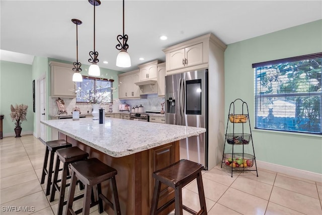 kitchen featuring light tile patterned floors, stainless steel appliances, light stone countertops, and backsplash