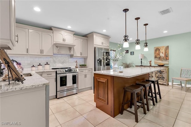 kitchen featuring visible vents, a breakfast bar, a kitchen island, backsplash, and stainless steel appliances