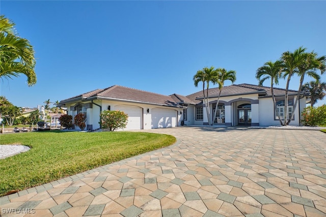 mediterranean / spanish-style house featuring french doors, a garage, a tile roof, and stucco siding