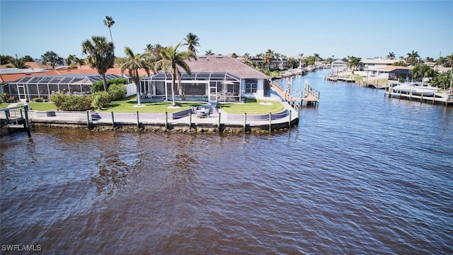 view of dock with a lanai, a lawn, and a water view