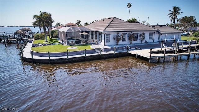 dock area featuring boat lift, glass enclosure, a yard, and a water view