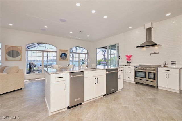 kitchen featuring wall chimney range hood, a healthy amount of sunlight, appliances with stainless steel finishes, and a sink