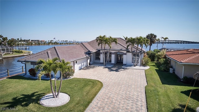 view of front of house featuring a garage, a water view, driveway, and a tiled roof