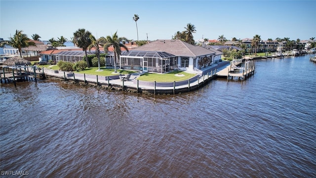 dock area with boat lift, glass enclosure, a yard, and a water view