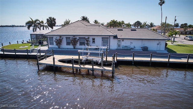 dock area featuring glass enclosure, a lawn, a water view, and boat lift