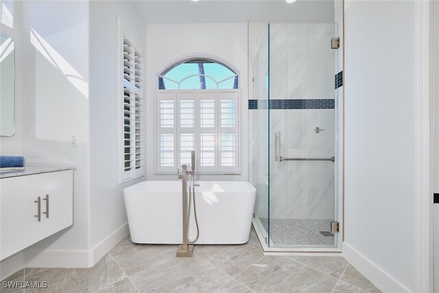 bathroom featuring baseboards, a soaking tub, a stall shower, and vanity