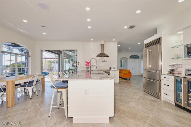 kitchen featuring range hood, light stone counters, recessed lighting, and appliances with stainless steel finishes