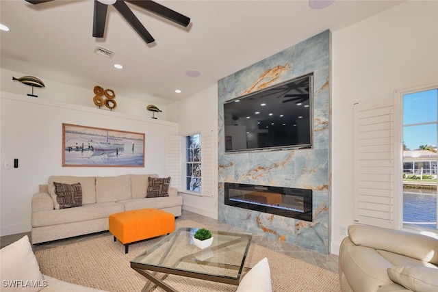 living area featuring a ceiling fan, baseboards, visible vents, recessed lighting, and a large fireplace