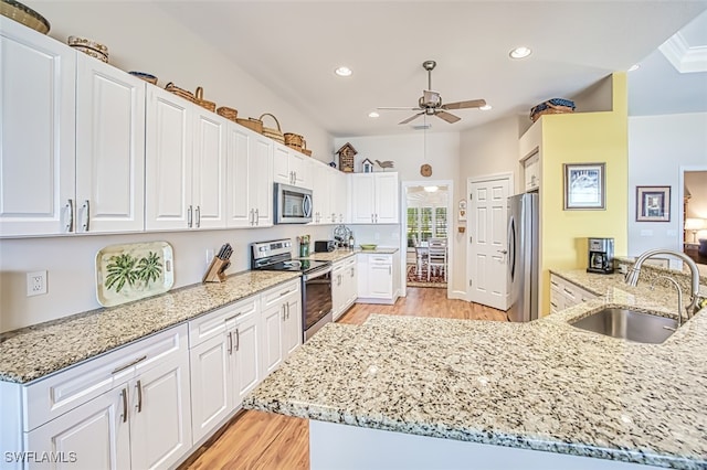 kitchen with a sink, light stone countertops, light wood-style floors, and appliances with stainless steel finishes