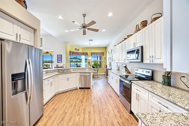 kitchen with a peninsula, light wood-style flooring, a sink, appliances with stainless steel finishes, and white cabinetry