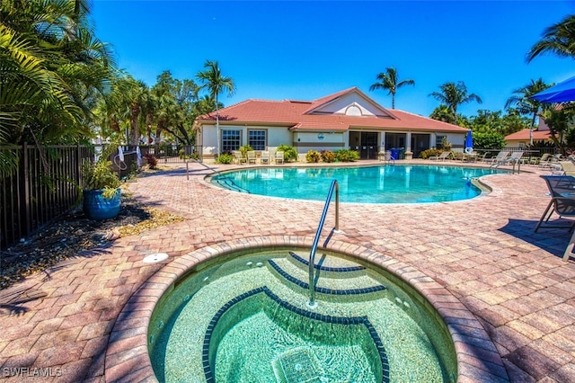 community pool with a patio area and fence