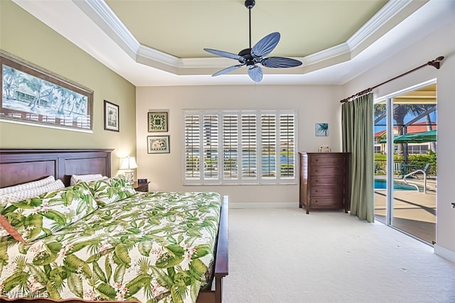 carpeted bedroom featuring a tray ceiling, access to exterior, and crown molding