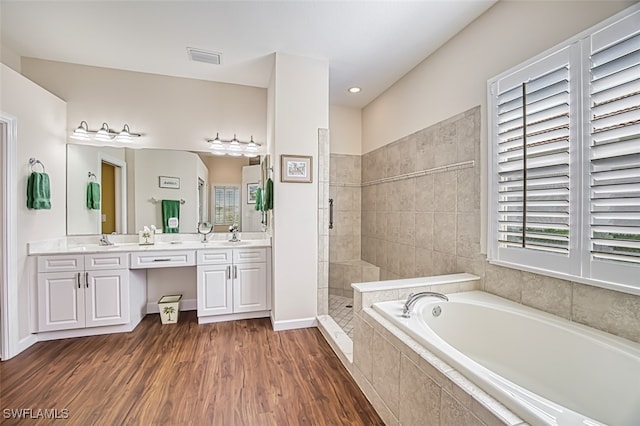 bathroom featuring a walk in shower, double vanity, wood finished floors, a bath, and a sink