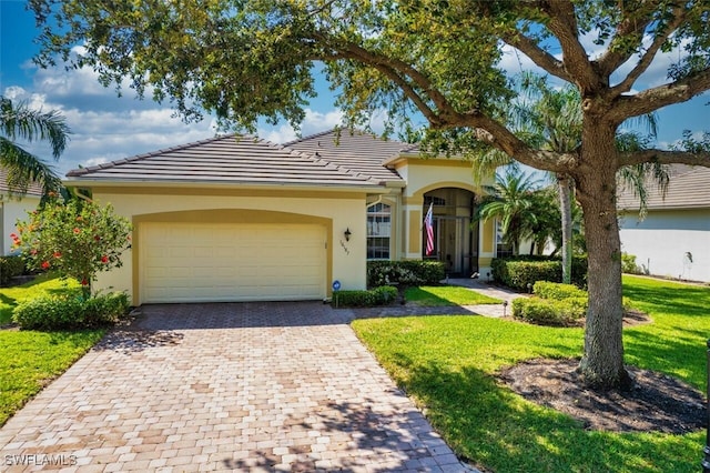 view of front of property featuring an attached garage, stucco siding, a front lawn, a tile roof, and decorative driveway