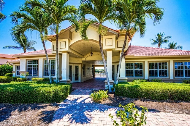 rear view of house with stucco siding, french doors, and a tile roof