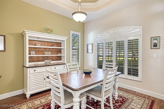 dining space with a tray ceiling, crown molding, baseboards, and dark wood-type flooring