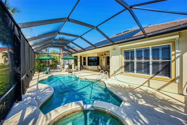 view of swimming pool featuring a patio area, glass enclosure, a pool with connected hot tub, and a ceiling fan