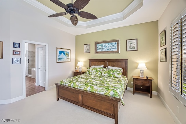 carpeted bedroom featuring a ceiling fan, a tray ceiling, crown molding, and baseboards