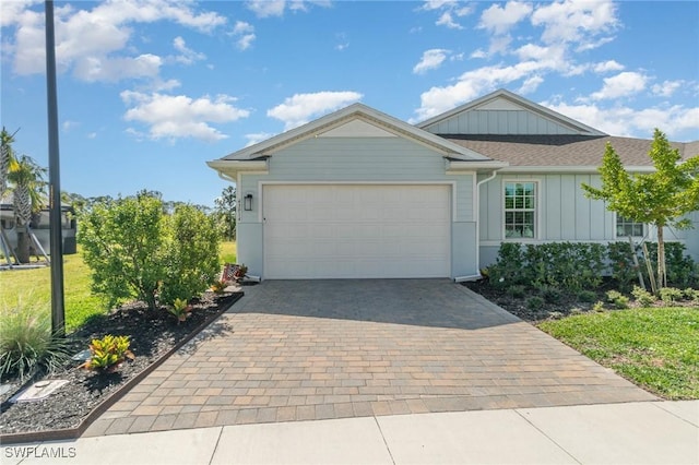 single story home with board and batten siding, a front yard, decorative driveway, and a garage